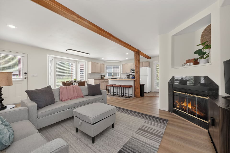 Settle into your stylish open-concept retreat where a cozy fireplace meets bright natural light. The exposed beam adds rustic charm, while modern comforts invite you to unwind in style.
