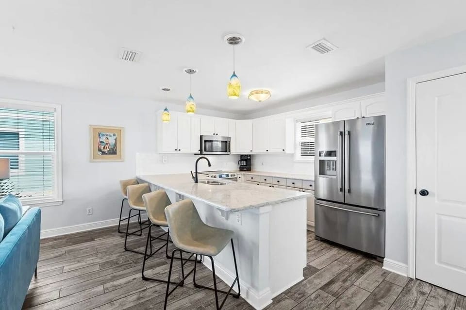 This bright kitchen features a spacious island for gathering, modern stainless appliances, and cheerful pendant lighting to set a welcoming vibe for your stay.