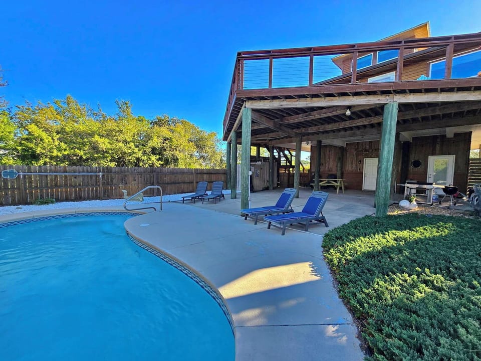 Dive into your private pool oasis, surrounded by lush landscaping and shaded lounging areas under the covered deck.