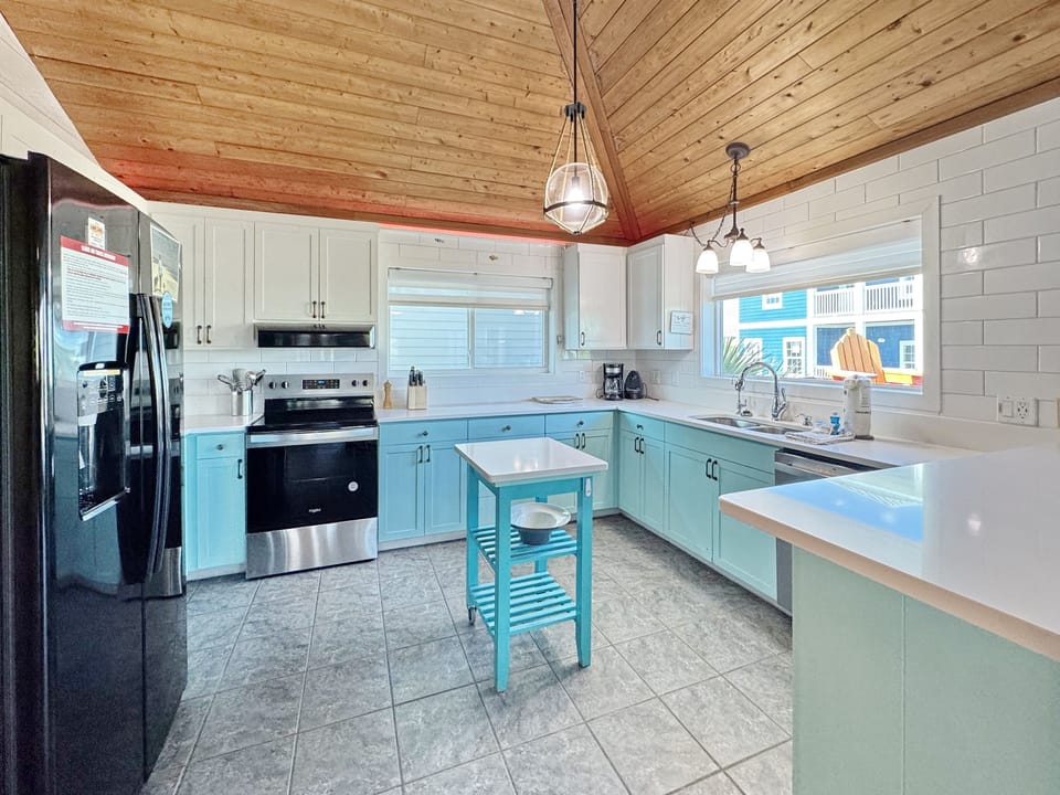 Cook up memories in your spacious kitchen featuring turquoise cabinets, modern appliances, and charming wood beam ceilings that create the perfect culinary retreat.