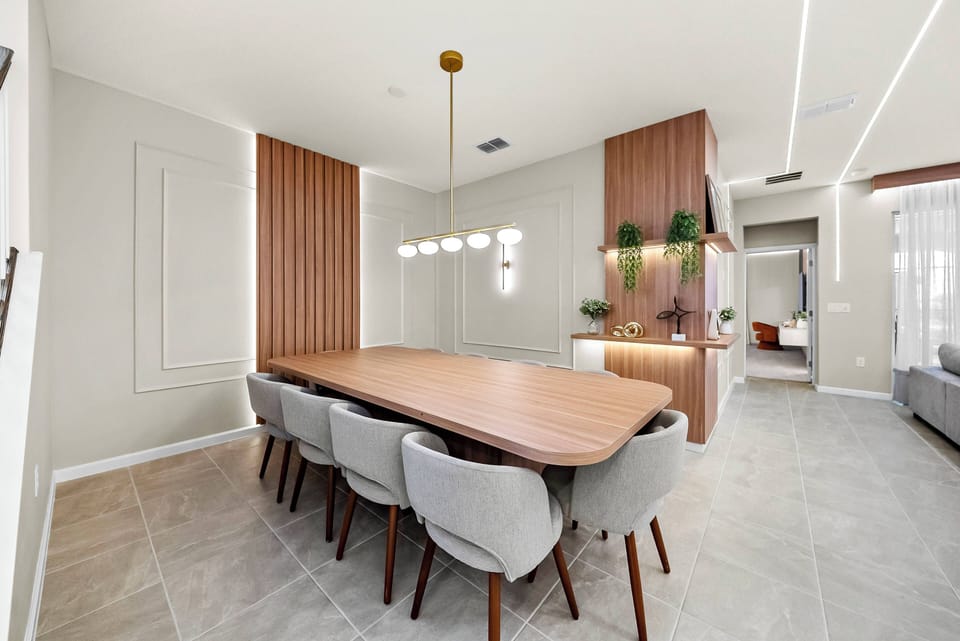 Enjoy stylish dining in this spacious area with a sleek wooden table and comfy upholstered chairs. The warm wood tones and soft neutral walls, enhanced by modern lighting, create an inviting atmosphere for your meal.