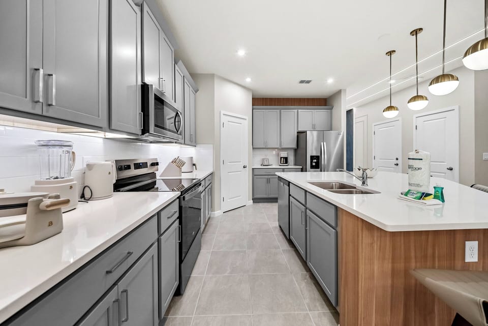 Experience our stylish kitchen with sleek gray cabinetry and a warm wood island, perfect for your culinary adventures. The spacious layout, polished countertops, and modern pendant lighting create an inviting cooking atmosphere.