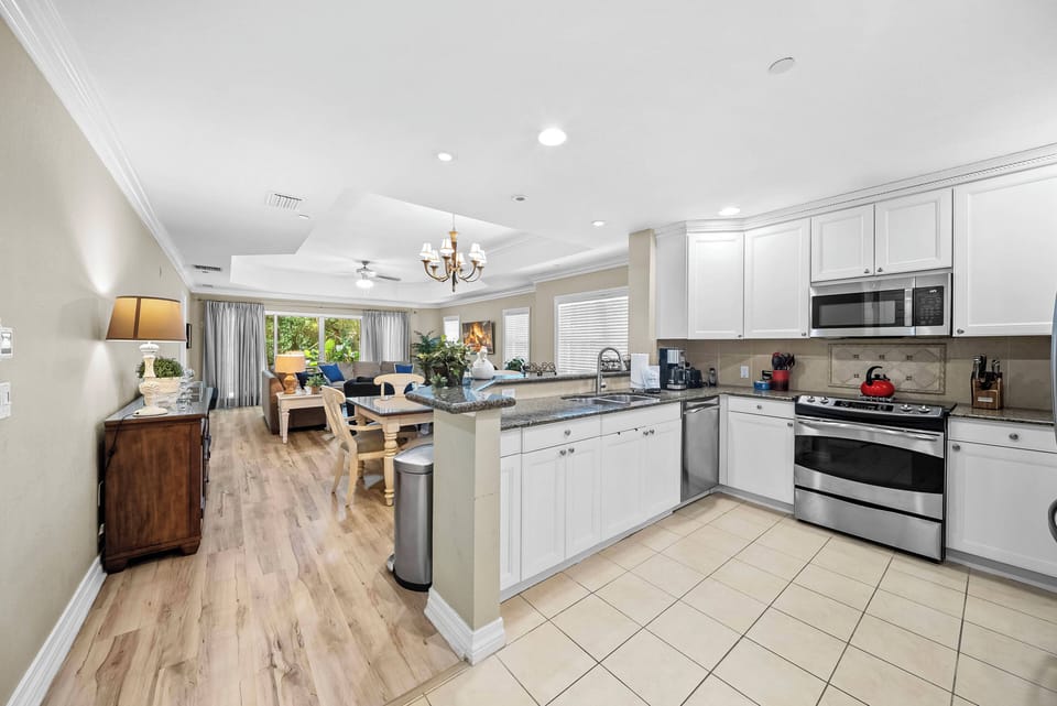 Experience the heart of your stay in this bright kitchen featuring sleek stainless steel appliances and elegant white cabinetry. The open layout seamlessly connects to a cozy dining area, perfect for enjoying meals together.