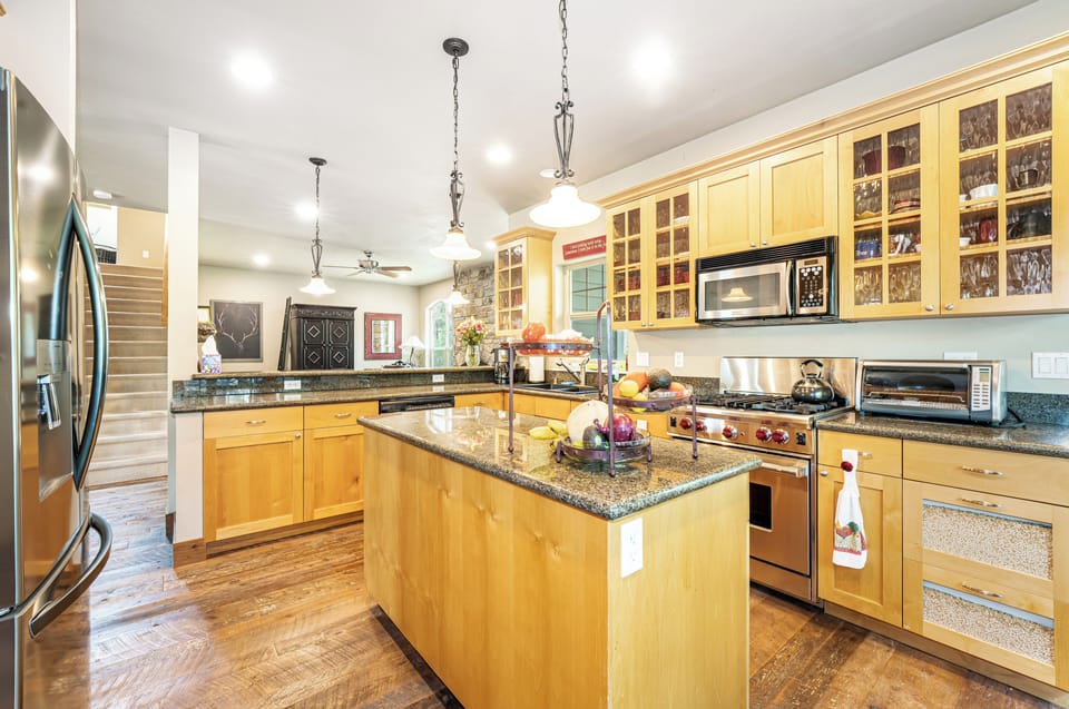 Your gourmet kitchen features warm wood cabinetry, granite counters, and stainless appliances—perfect for preparing memorable meals with plenty of counter space and natural light.