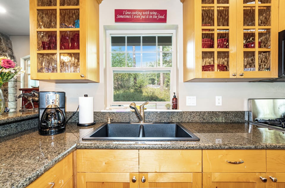 Your kitchen features granite counters, ample cabinetry, and a charming window overlooking tranquil greenery—perfect for sipping morning coffee while enjoying nature's calm right from the sink.