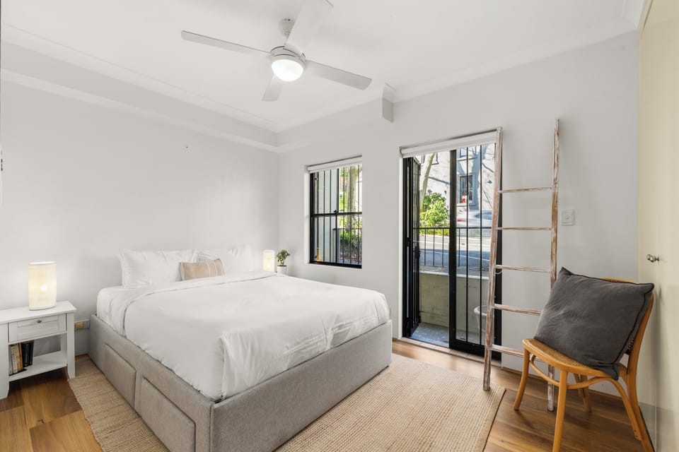 Relax in the bedroom, where a queen bed, ceiling fan, portable heater, bedside lighting and street views create a comfortable retreat after exploring Surry Hills.