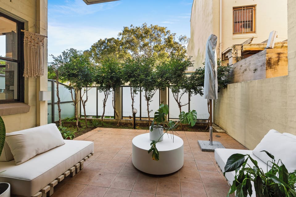 Spend sunny afternoons in the private courtyard, where cushioned outdoor seating, established greenery and an umbrella create a secluded pocket for coffee, reading or drinks in the fresh air.