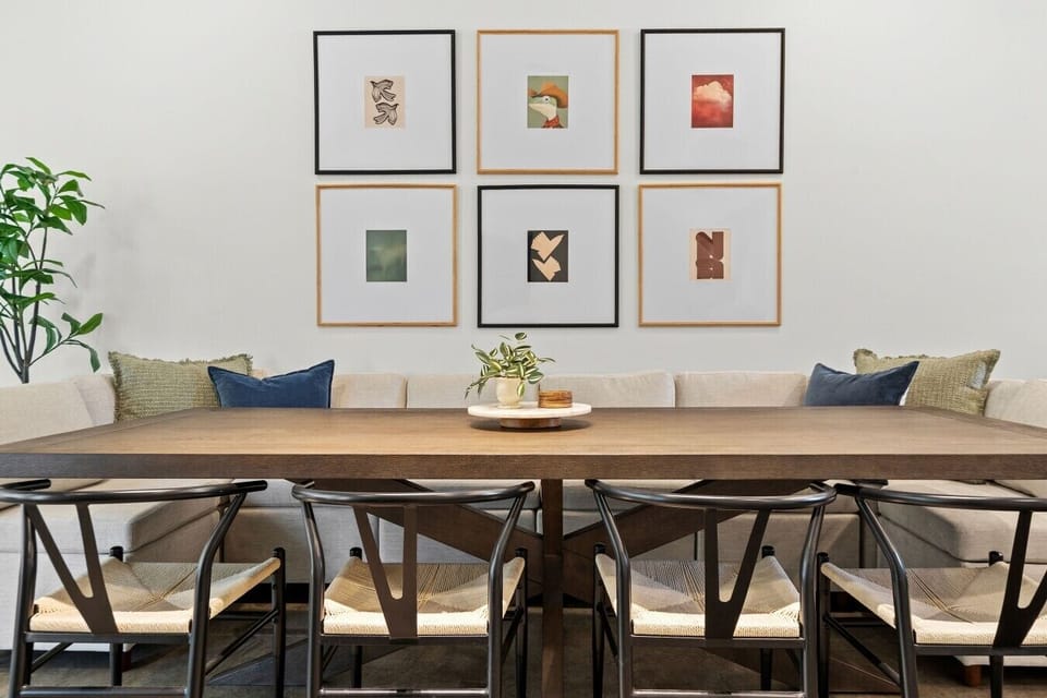 Linger over meals at the dining table with cushioned bench seating and a warm, art-filled backdrop.