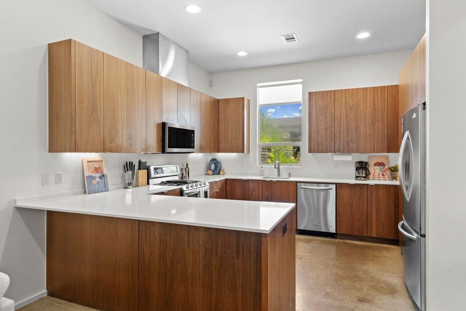 Cook with ease in the walnut kitchen featuring quartz counters, a gas range, and full stainless appliances.