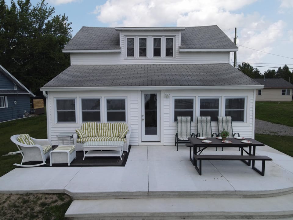 Back of the cottage with the spacious deck, picnic table, and additional outdoor seating.