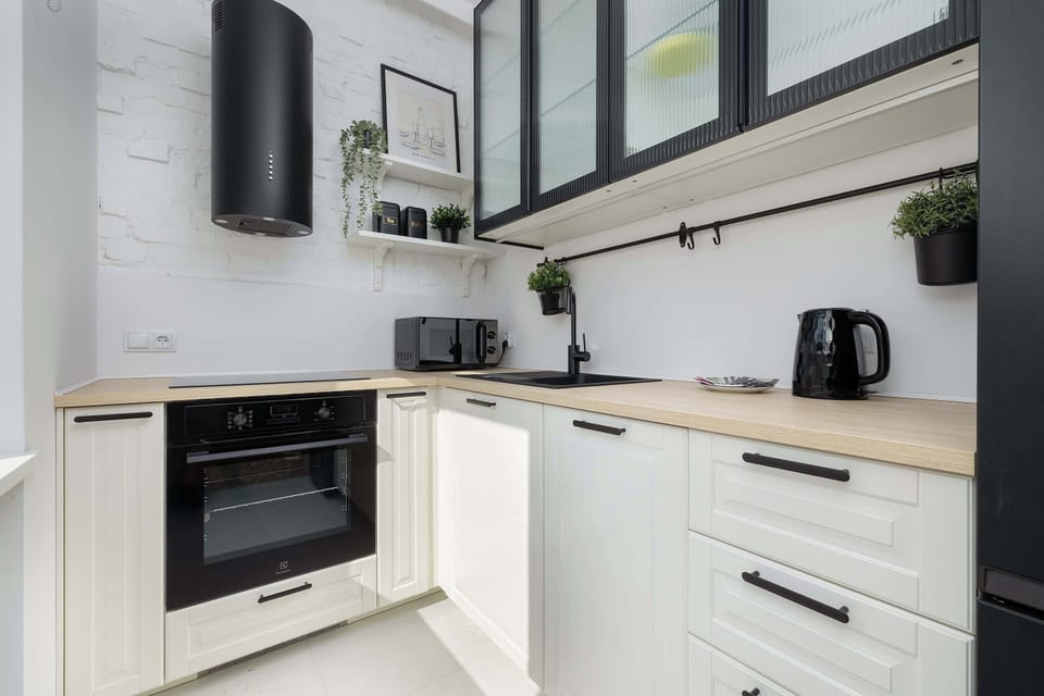 A modern white kitchenette with built-in appliances and plenty of storage space.