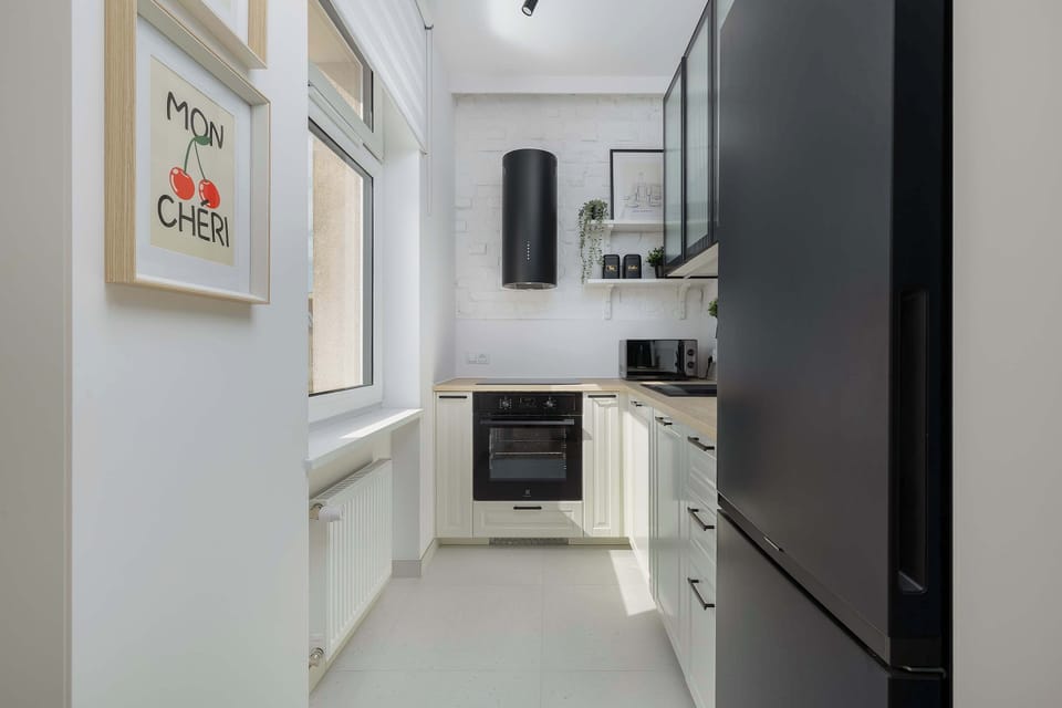 A compact and modern kitchenette with built-in appliances and a washing machine nearby.