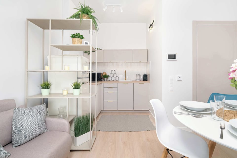 Modern kitchenette with white cabinets, open shelving, a sink, a cooking area and dining space.