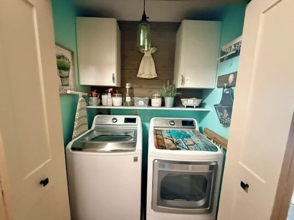 Charming laundry nook with modern washer/dryer, storage, and hanging rack
