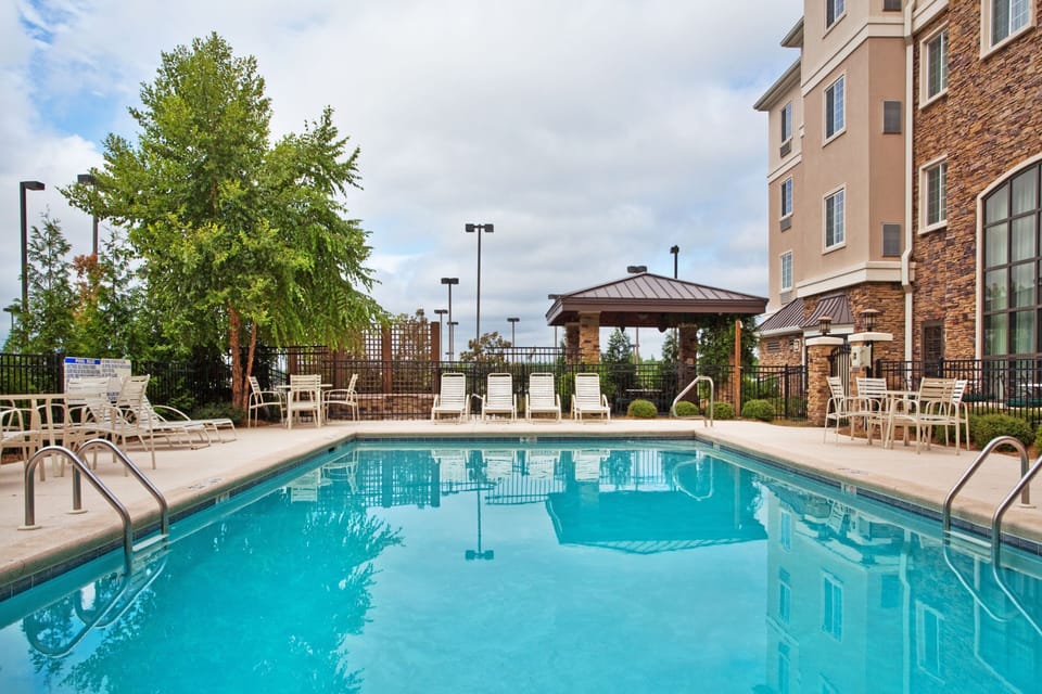 Unwind by the sparkling pool surrounded by lush greenery and cozy lounge chairs.
