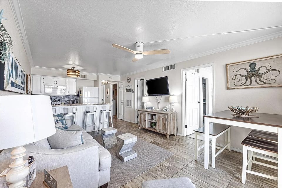 Bright coastal living space with open kitchen, bar seating, and dining nook