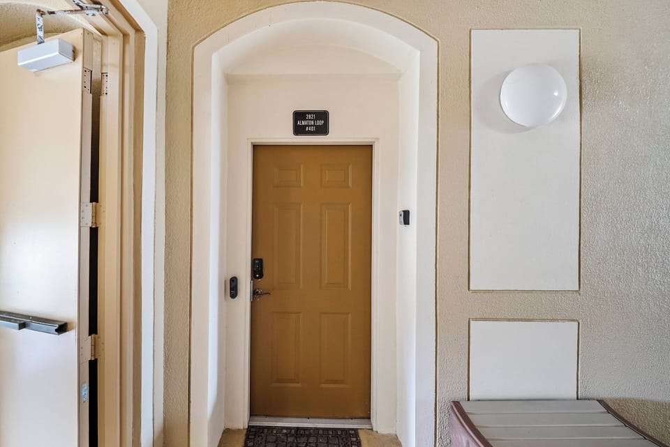 Step into a welcoming entryway featuring warm beige walls and a classic arched doorway that sets the tone for your stay. The soft lighting and stylish wall sconce create an inviting atmosphere, making you feel right at home.