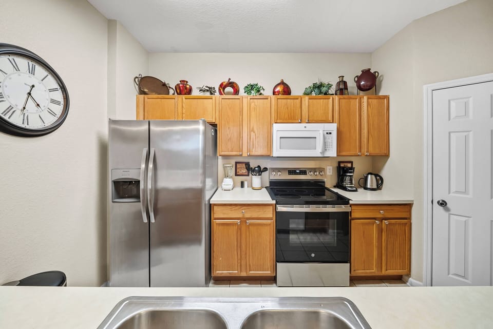Discover a well-equipped kitchen with warm wooden cabinets and stainless steel appliances that complement the neutral walls, while a charming clock adds character, creating the perfect space for your culinary adventures.