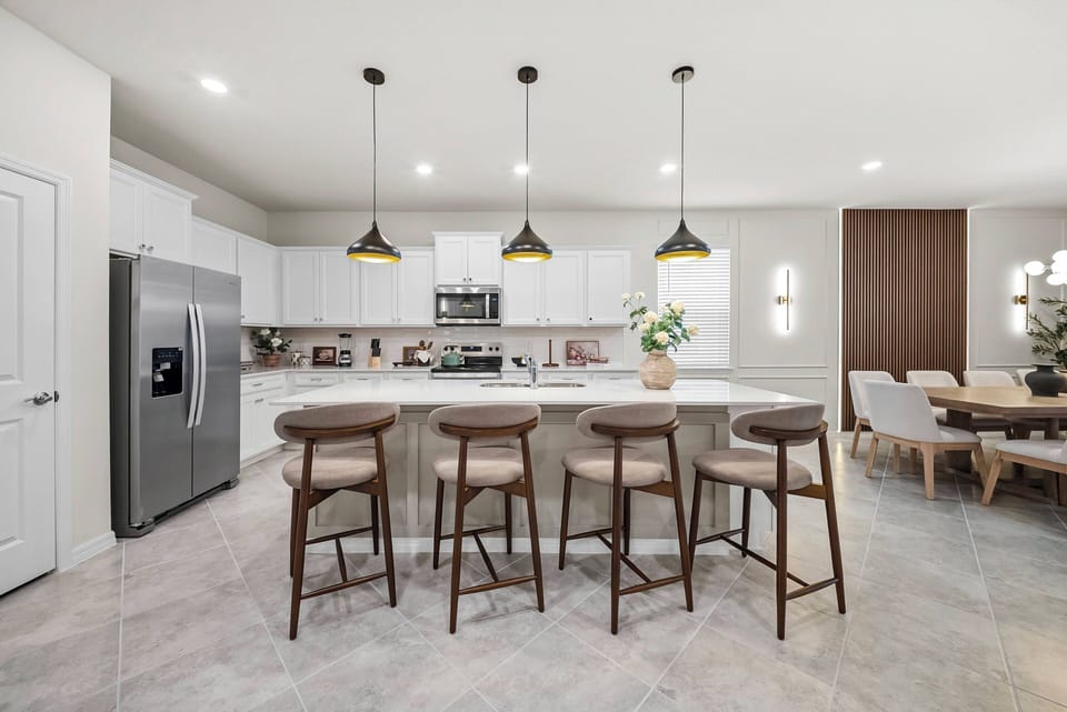Savor culinary delights in a stylish kitchen with sleek white cabinetry and a spacious island for cozy bar seating. Pendant lights add warmth, while modern appliances make meal prep easy, connecting effortlessly to the dining.