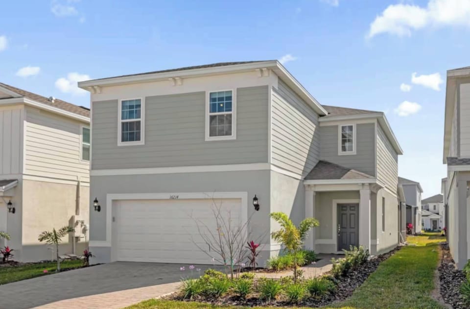 The charming light gray exterior with crisp white trim creates a fresh and inviting look, while the well-maintained landscaping and vibrant greenery warmly welcome you to explore the delightful surroundings.