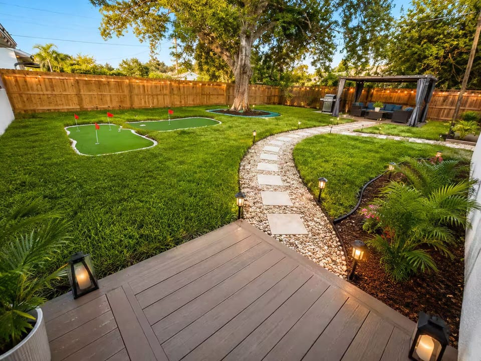 Step into a peaceful backyard with a lush lawn and a winding garden path.