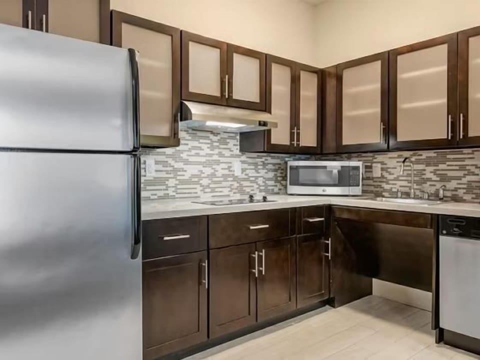 Kitchen with stainless steel appliances, dark cabinetry, and mosaic tile backsplash