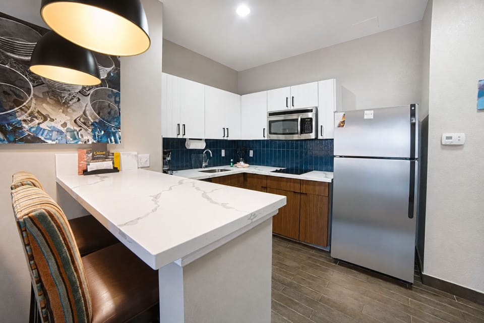 Full kitchen with bar island, bar stools, and pendant lighting.