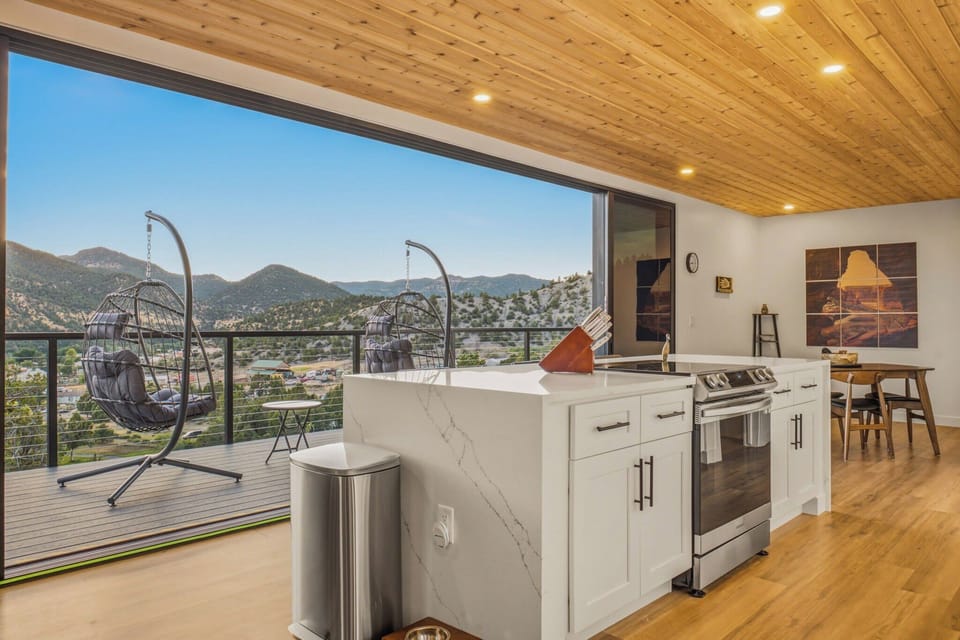 Cook with a view! This modern kitchen opens onto a spacious balcony with stunning mountain vistas and comfy hanging chairs.