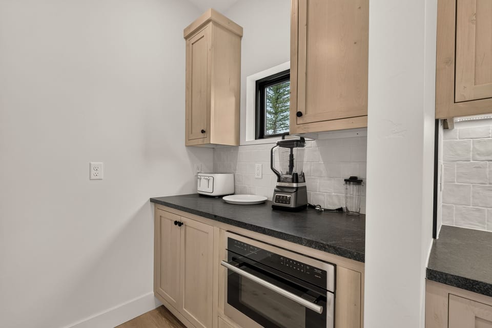 Modern kitchenette with sleek finishes, natural light, and handy appliances