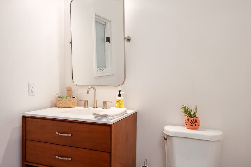 Bathroom vanity with sink, modern faucet, curved mirror, and essential amenities.
