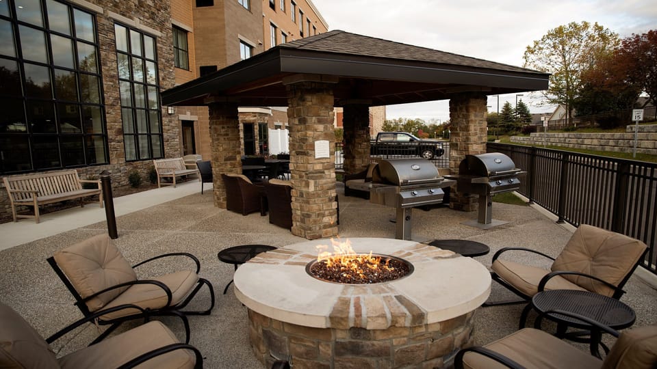 Outdoor gazebo with two BBQ grills, firepit, and cushioned seating