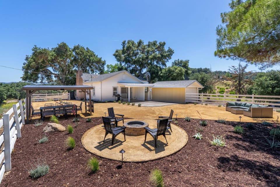 Spacious fenced yard with fire pit, pergola dining, and lounge seating
