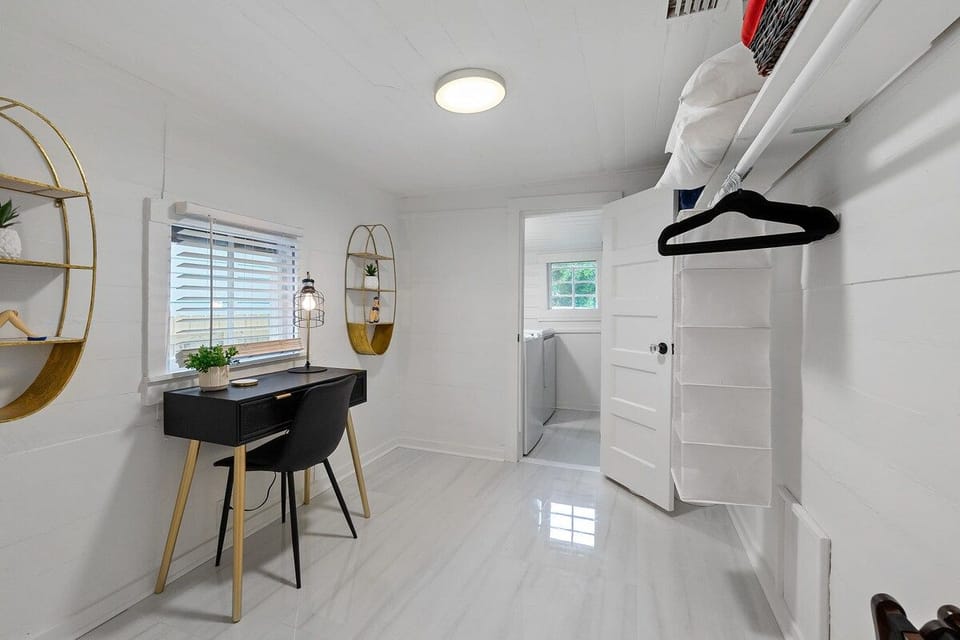 Bright minimalist room with workspace, storage, and laundry access