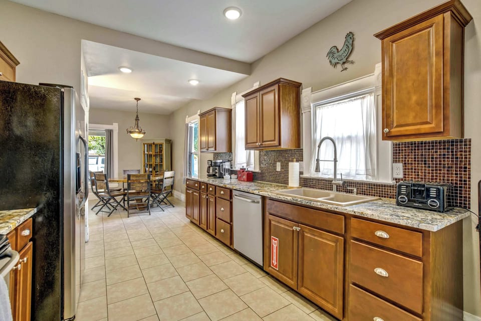 From the other end, the kitchen opens back toward the dining room, with a window set above the sink, recessed lighting overhead, and generous granite counter space on both sides for spreading out while you cook together.