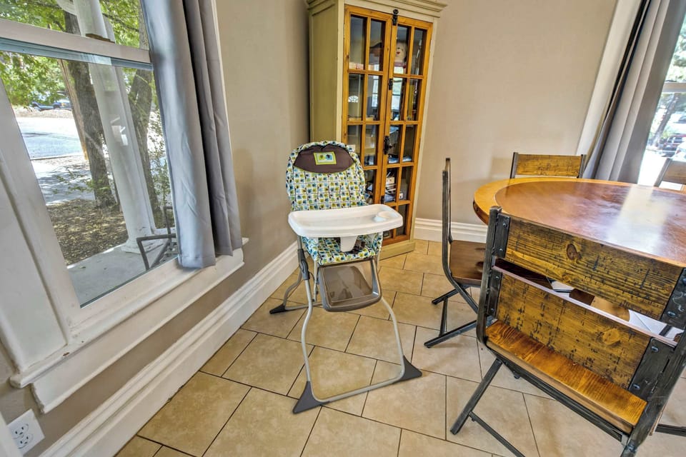 A high chair is available for the littlest guests, tucked into the dining nook beside a tall built-in cabinet with glass front doors. Windows on two sides wrap the corner in soft daylight through the entire morning hours.