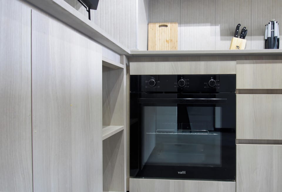 Modern kitchenette with built-in oven and sleek wood finishes