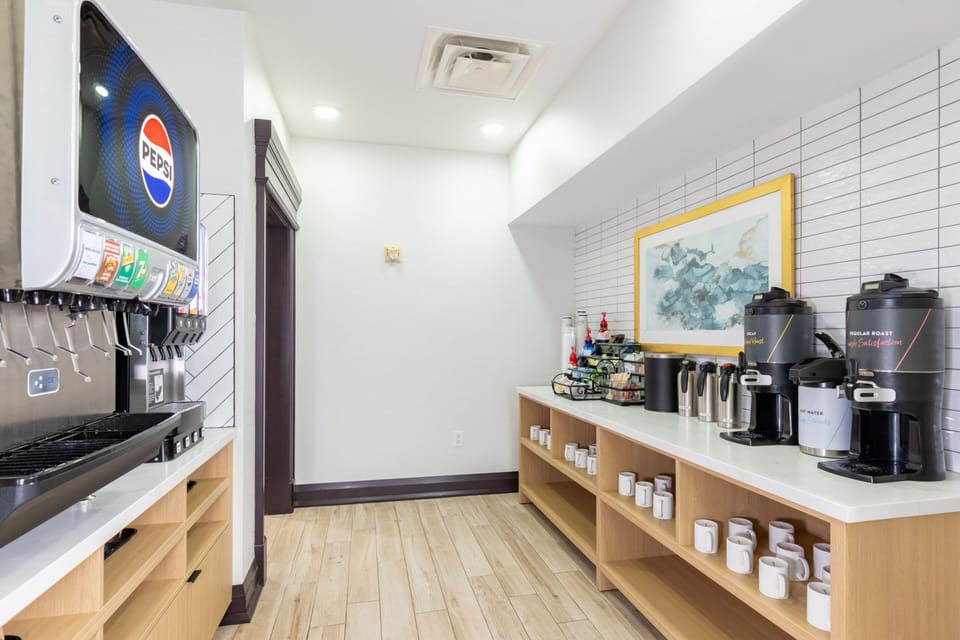 Beverage station with soda fountain, coffee machines, and assorted condiments.