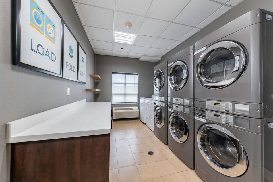 Guest laundry room with stackable washers, dryers, and folding counter.