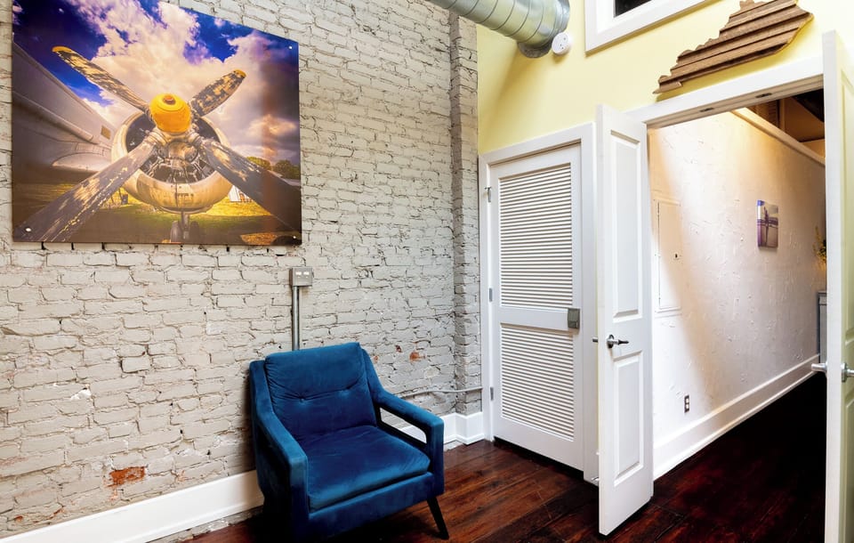 Grab a good book and sit in the rich blue armchair by the bright white doors. The rustic brick and modern art create a lovely corner to relax.