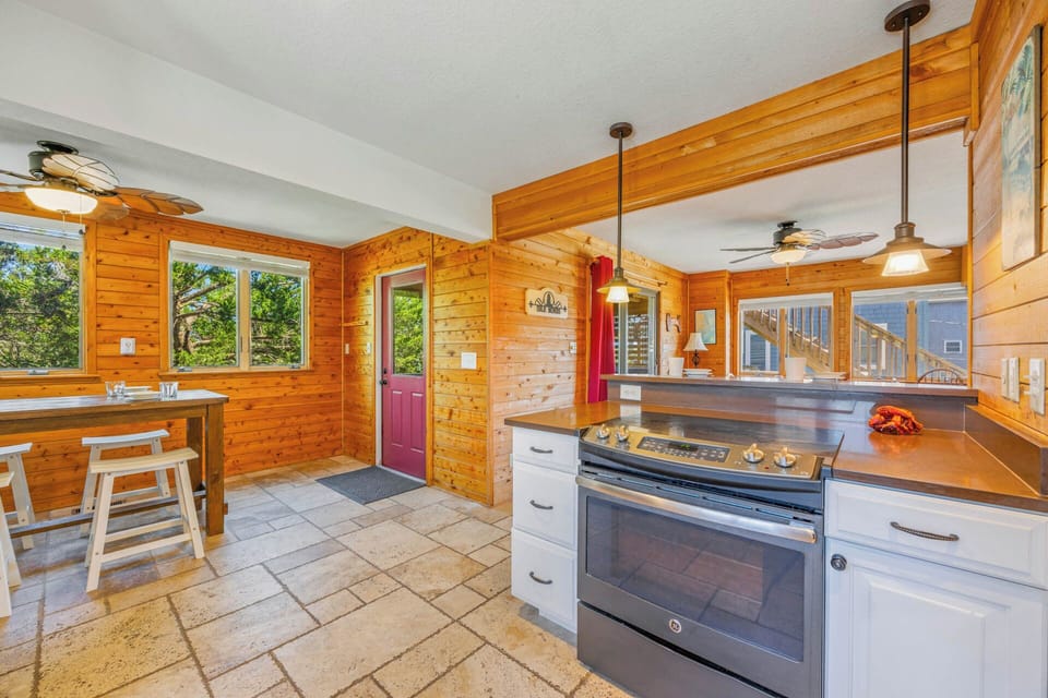 Cook your favorite meals in this warm, rustic kitchen featuring modern appliances and charming knotty pine walls that make you feel right at home.