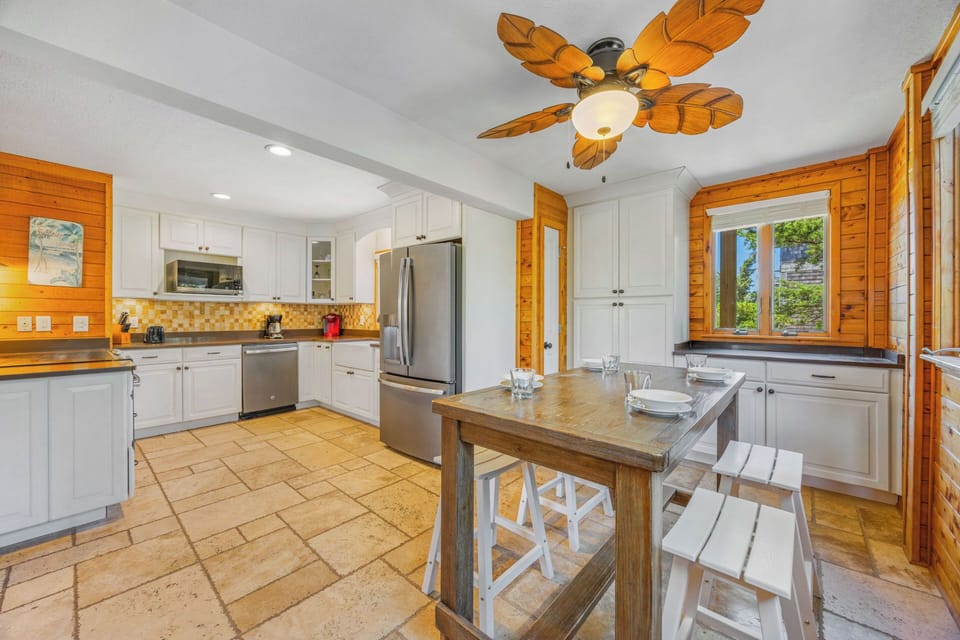 Step into your bright, beach-inspired kitchen with warm wood accents and a breezy tropical ceiling fan. A charming dining island awaits your morning coffee and home-cooked meals.