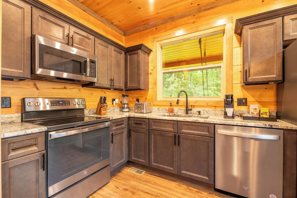 Step into your fully equipped kitchen where warm wood tones meet modern convenience. Granite countertops, stainless steel appliances, and a window overlooking the surrounding forest make meal prep a delight.