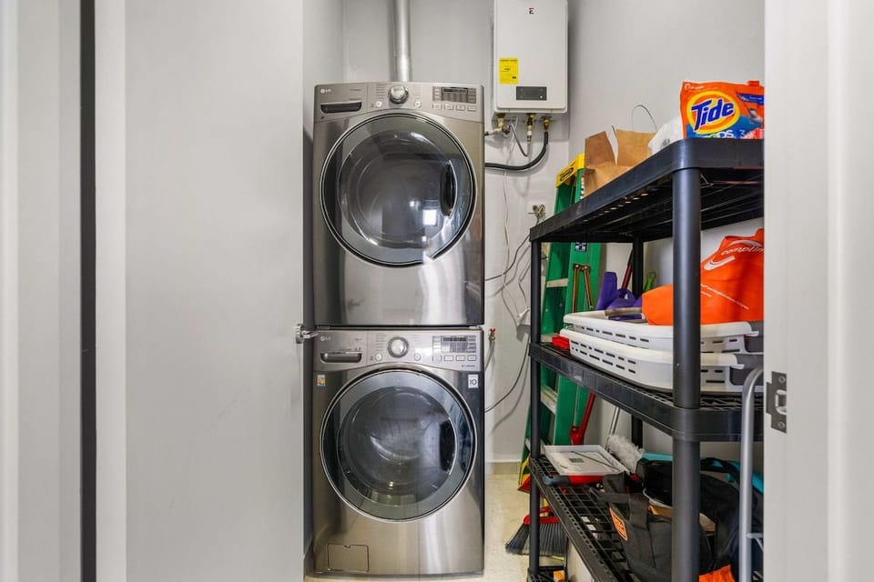 Dedicated utility closet equipped with a high-end stacked LG washer and dryer, a water heater, and convenient storage shelving.