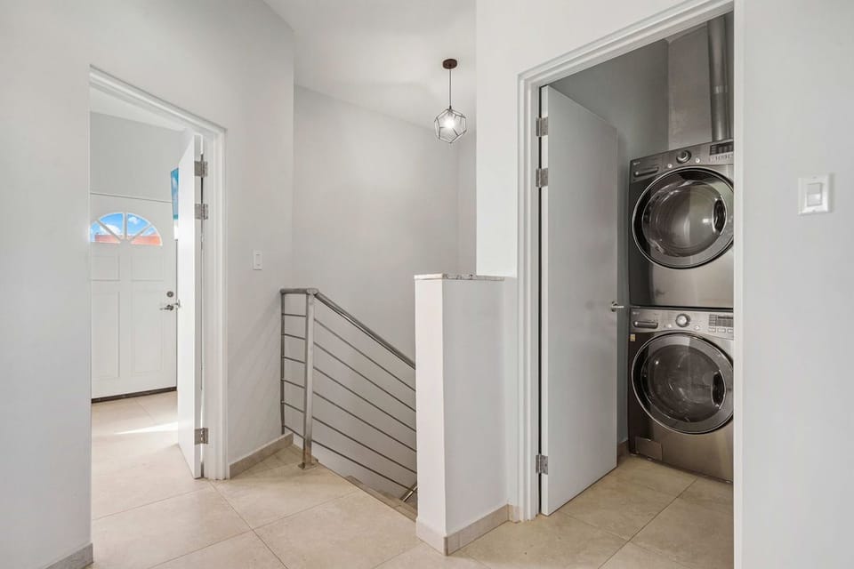 Convenient upper-level hallway featuring a dedicated laundry nook with a high-end stacked washer and dryer.