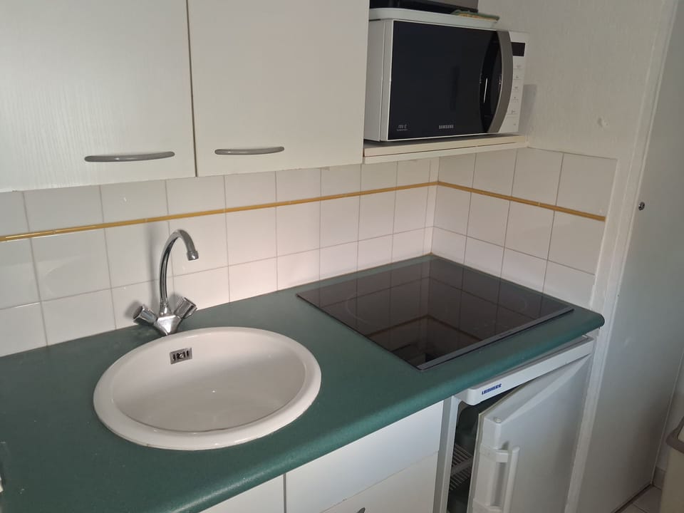 A kitchenette with electric hob, microwave, and fridge makes light meals easy between days at the beach