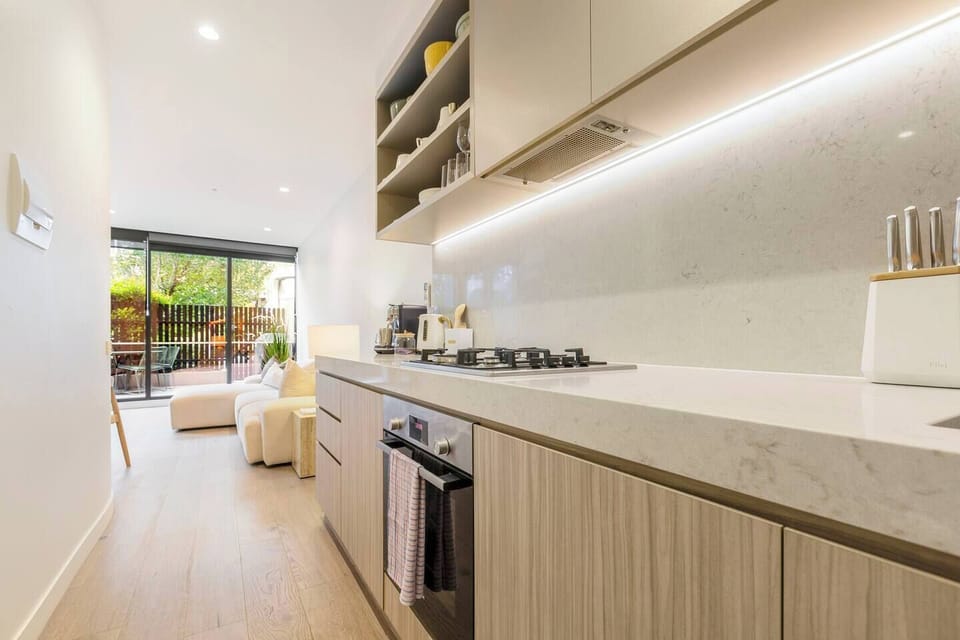 The sleek, modern kitchen is fully equipped with premium appliances and generous bench space for easy meal preparation.