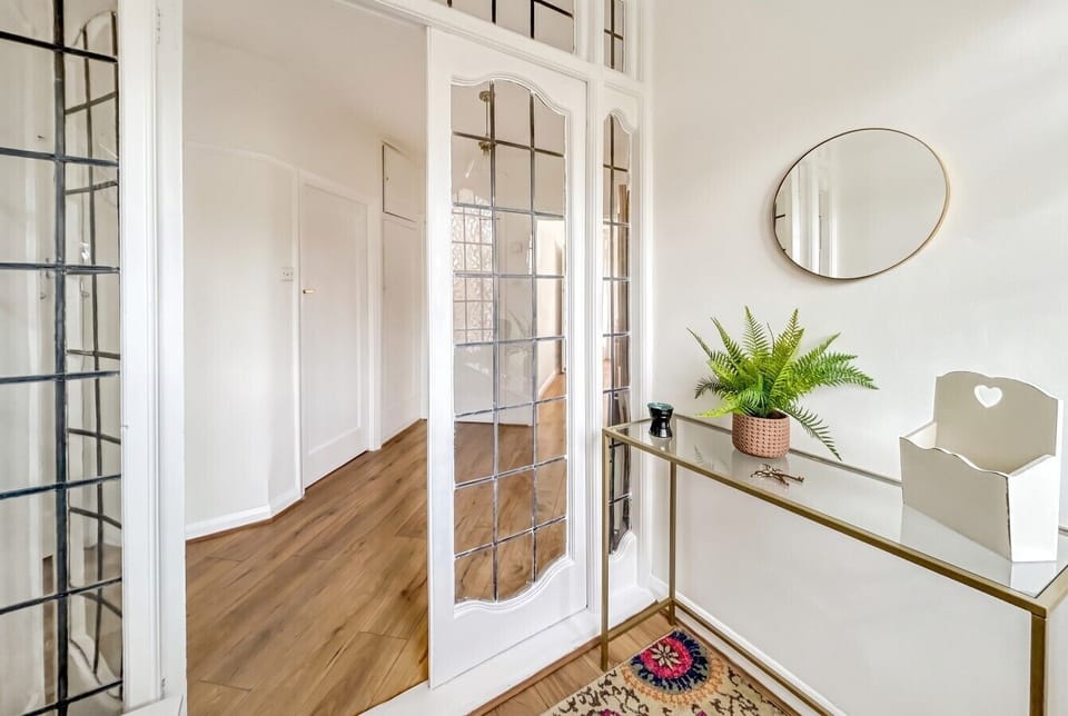 An inner hallway with tall glazed internal doors, a console table with a plant, and a round mirror, connecting the entrance to the rest of the property.