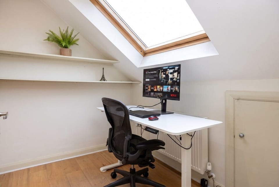 Focused workspace with a computer and an ergonomic chair under a skylight.