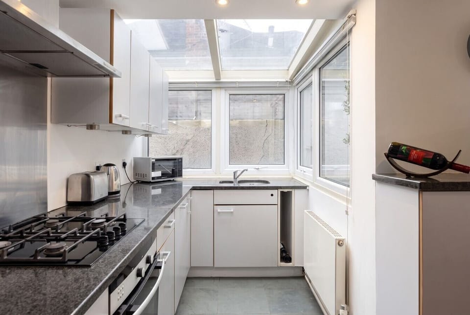 Bright galley kitchen under a skylight, fully equipped for home cooking.