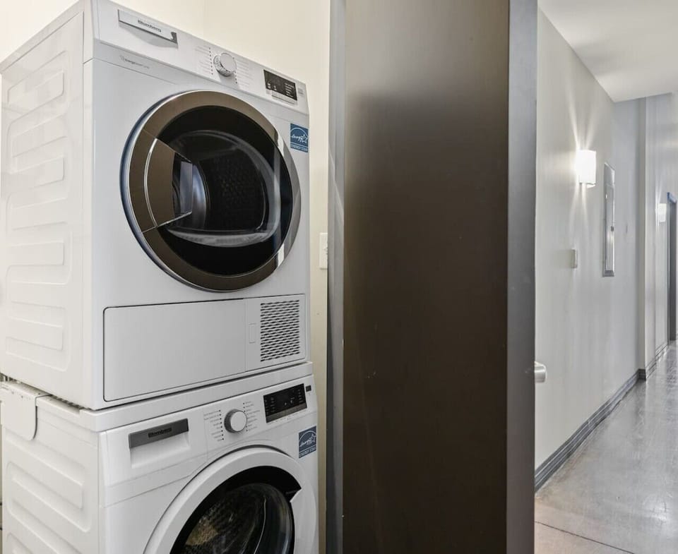 Clean apartment laundry area featuring a stacked washer and dryer next to a hallway.